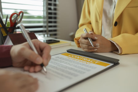 A man signs a contract after agreeing to buy a house with an agent. The agent explains the details of the contract to the buyer before signing it. Home purchase contractの写真素材