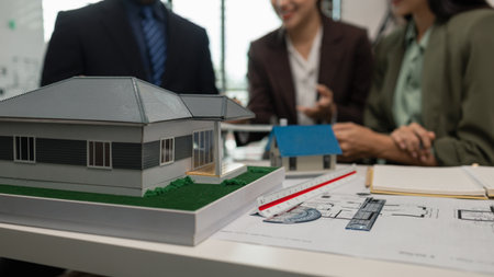 Architects work with engineers and contractors in the office to check the accuracy of the first draft plan, blueprint on the desk, three architects are working together in the workplaceの写真素材