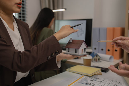 an architect is working in the office with his team, blueprint on the desk, contractor working with an engineer team, engineering and architecture, house model on the deskの写真素材