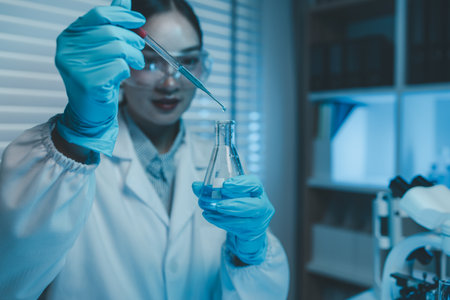 a female scientist is experimenting with chemicals in a lab, science experiments often require a lot of equipment, laboratory, microscope, a chemist examines a sample of a liquid in a laboratoryの写真素材