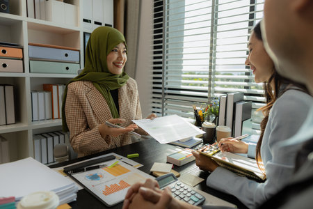 group of businessmen are discussing in an office. businessmen of different culture are meeting to make products that are appropriate and religiously correct. A businesswoman is wearing a hijab.の写真素材