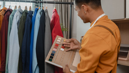 designer shop owner is working in his studio, use a lot of fabric to make clothes, design fashionable clothes for customer, sewing is an important tool for designer.の写真素材