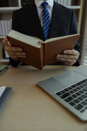 Businessman dressed in a suit is working in an office at a company. A senior executive is in a private office and doing many things. The atmosphere of a private office is calm and peaceful.の写真素材