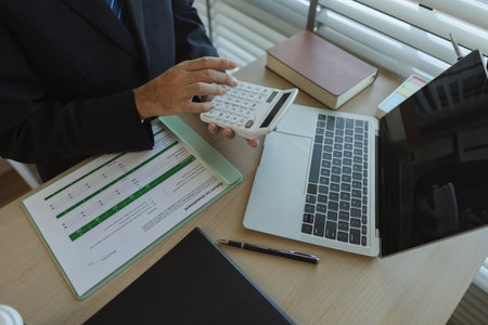 A businessman is sitting in an office with documents in his hands to analyze data. An executive of a...