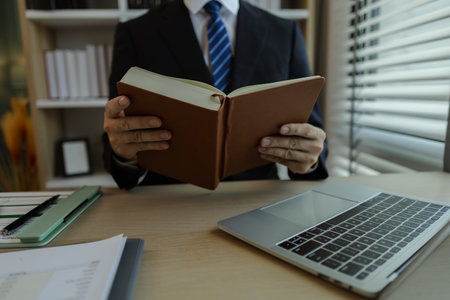 Businessman dressed in a suit is working in an office at a company. A senior executive is in a private office and doing many things. The atmosphere of a private office is calm and peaceful.の写真素材