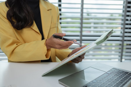 a female executive office working is sitting and working in her private office, a female company owner sits in her company's office, entrepreneur, businesswoman works with a lot of paperworkの写真素材