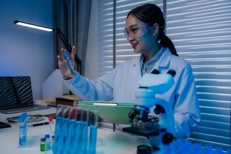 a female scientist is experimenting with chemicals in a lab, science experiments often require a lot of equipment, laboratory, microscope, a chemist examines a sample of a liquid in a laboratoryの写真素材