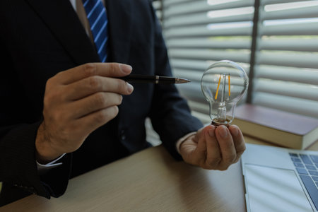 Businessman dressed in a suit is working in an office at a company. A senior executive is in a private office and doing many things. The atmosphere of a private office is calm and peaceful.の写真素材