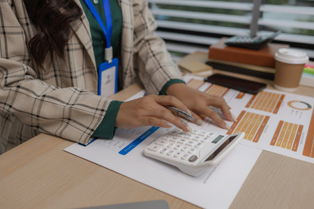an employee sits working in an office full of documents that need to be completed on time, the marketing team leader is reviewing documents related to marketing informationの写真素材