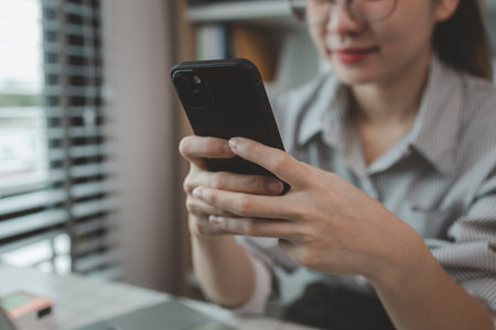 a businesswoman is using an electronic device to search and send information to her team, the marketing team leader is reviewing documents related to marketing dataの写真素材