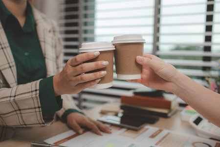 two female employees are celebrating after they successfully completed a project, business people celebrating success in an office, cheerful businesswomen shaking hands in meeting room,の写真素材