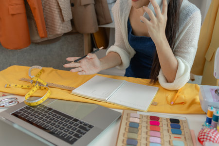 beautiful young lady tailor at work, beautiful female designer at design studio, crop view of fashion designer at work, woman in tailor workshop, clothing designer in workshop.の写真素材