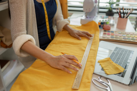 female fashion designer in her workshop studio, fashion designer working with fabric cutouts, beautiful fashion designer is making clothes with high quality fabric, dressmaker, material, clothingの写真素材