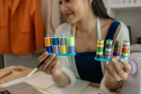 female fashion designer using sewing equipment in workshop, portrait of a young woman working in the fabric workshop, view of young tailor working in her studioの写真素材