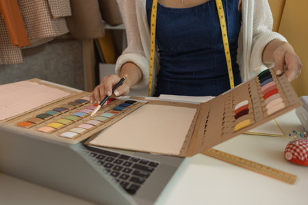 female fashion designer in her workshop studio, fashion designer working with fabric cutouts, beautiful fashion designer is making clothes with high quality fabric, dressmaker, material, clothingの写真素材