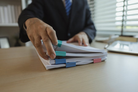 Businessman dressed in a suit is working in an office at a company. A senior executive is in a private office and doing many things. The atmosphere of a private office is calm and peaceful.の写真素材