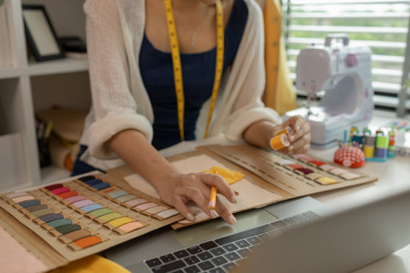 female fashion designer in her workshop studio, fashion designer working with fabric cutouts, beautiful fashion designer is making clothes with high quality fabric, dressmaker, material, clothingの写真素材