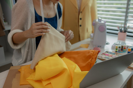 female fashion designer using sewing equipment in workshop, portrait of a young woman working in the fabric workshop, view of young tailor working in her studioの写真素材