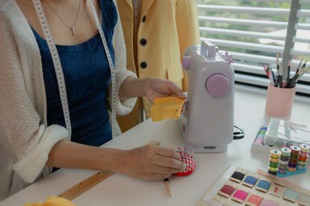 female fashion designer using sewing equipment in workshop, portrait of a young woman working in the fabric workshop, view of young tailor working in her studioの写真素材