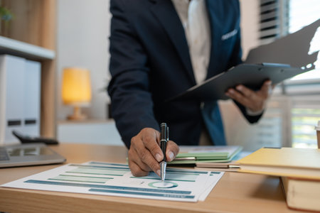 middle aged professional businessman wearing white shirt and suit happily smiling in office, a middle-aged, dark-haired businessman in a suit is happily working at his desk in the officeの写真素材