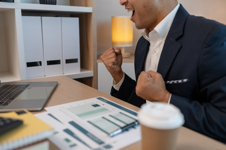 Young businessman cheering, cheerful businessman screaming of joy in the office, middle aged businessman punching air, male businessman making a happy gesture, happy businessman in his private officeの写真素材