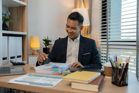 Image of handsome businessman is working in office, cheerful businessman entrepreneur professional working while sitting at office desk, accountant, marketing, employee is working alone in the officeの写真素材