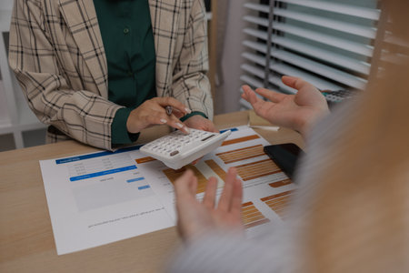 data analysis staff are helping to check data in various documents before summarizing and presenting them to the meeting, two business colleagues working together on paperwork at officeの写真素材