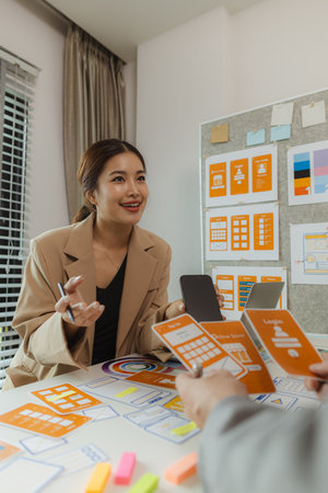 A team of web developers discusses how to best organize a website layout. They share ideas on how to best optimize a digital product, ux ui team is working together in the officeの写真素材