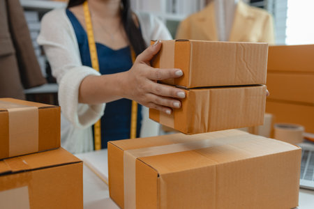 a designer is preparing products to send to customers by mail, a female dressmaker is selling her products online to increase her income, female industrial tailor at workの写真素材