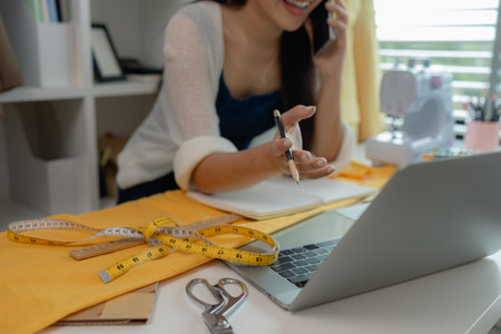 beautiful young lady tailor at work, beautiful female designer at design studio, crop view of fashion designer at work, woman in tailor workshop, clothing designer in workshop.の写真素材