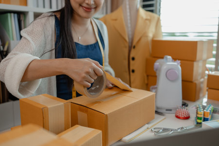 a designer is preparing products to send to customers by mail, a female dressmaker is selling her products online to increase her income, female industrial tailor at workの写真素材