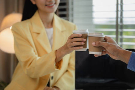 toast with coffee in the office, Happy businesspeople drinking coffee in the office, businessman enjoying a celebratory toast with coffee cups, business colleagues toasting on a break in the office.の写真素材