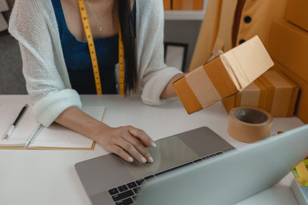 a designer is preparing products to send to customers by mail, a female dressmaker is selling her products online to increase her income, female industrial tailor at workの写真素材