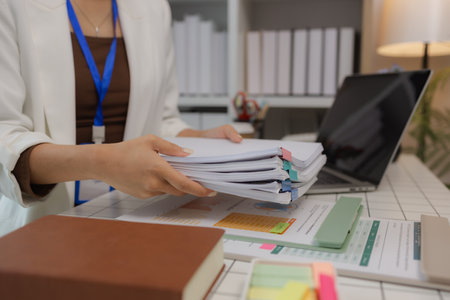there are a lot if documents pied up on the desk if the data analysis team leader, an employee sits working in an office full of documents that need to be completed on timeの写真素材