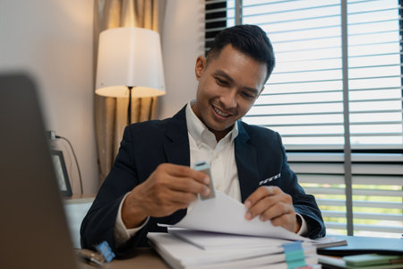 Image of handsome businessman is working in office, cheerful businessman entrepreneur professional working while sitting at office desk, accountant, marketing, employee is working alone in the officeの写真素材