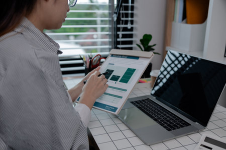 businesswoman working on laptop in her studio, businessperson working on a digital tablet and laptop...
