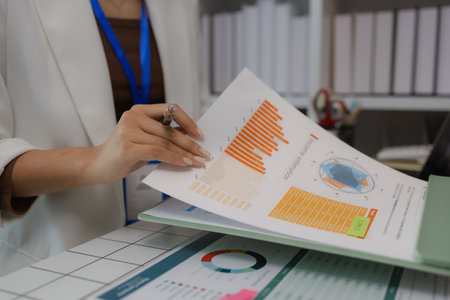 a businesswoman is sitting in her private office working on her desk with many documents to check, a lot of marketing documents were reviewed by the team leaderの写真素材