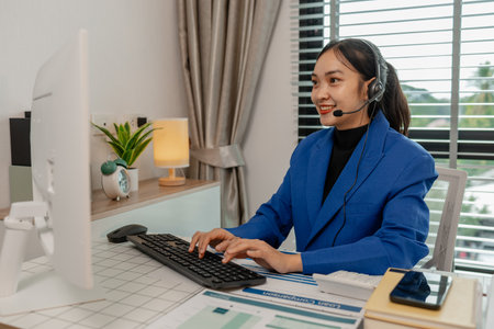happy smiling woman working in call center, call center worker, customer service representative using a headset while working at a call center, woman call center operator with headset using computerの写真素材