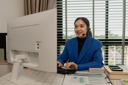 happy smiling woman working in call center, call center worker, customer service representative using a headset while working at a call center, woman call center operator with headset using computerの写真素材