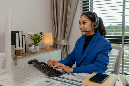 happy smiling woman working in call center, call center worker, customer service representative using a headset while working at a call center, woman call center operator with headset using computerの写真素材