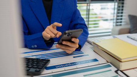 businesswoman sitting by the window with mobile phone at startup office, connection and woman typing on a phone for communication, female entrepreneur with smart phone and laptop working in officeの写真素材