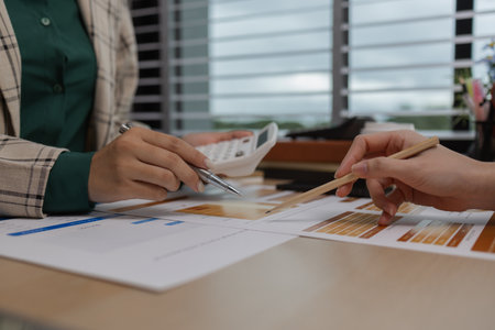 data analysis staff are helping to check data in various documents before summarizing and presenting them to the meeting, two business colleagues working together on paperwork at officeの写真素材