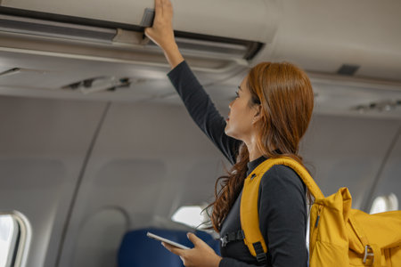 young happy woman in an airplane cabin, a beautiful asian woman travels by plane to a foreign country for vacation, atmosphere inside the plane, a woman performs various poses on an airplane.の写真素材