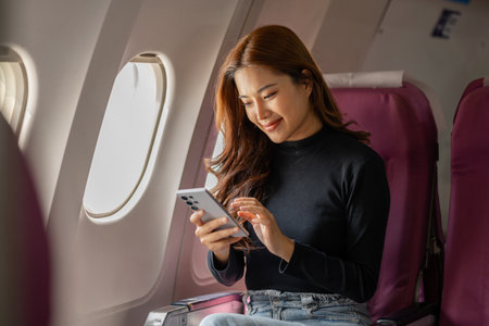 young happy woman in an airplane cabin, a beautiful asian woman travels by plane to a foreign...