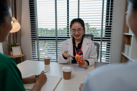 a female doctor is explaining the systems in the human body to two interns, three doctors are meeting to discuss the most appropriate treatment approach for the patientの写真素材