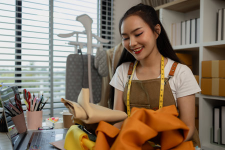 a beautiful tailor is working on her favorite craft in a studio filled with a variety of sewing supplies, fabrics and threads, designer, dressmaker, fashion, entrepreneurの写真素材