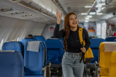 young happy woman in an airplane cabin, a beautiful asian woman travels by plane to a foreign country for vacation, atmosphere inside the plane, a woman performs various poses on an airplane.の写真素材