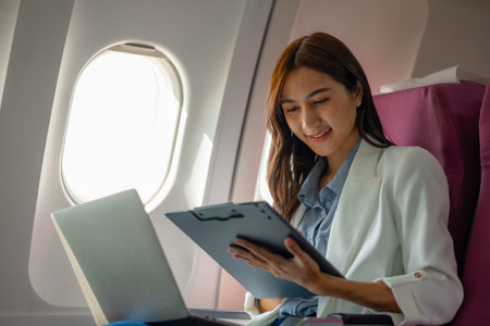 a beautiful businesswoman was traveling to negotiate a business with a business partner abroad by plane, while traveling she checked documents and worked to kill time, businessman, business tripの写真素材