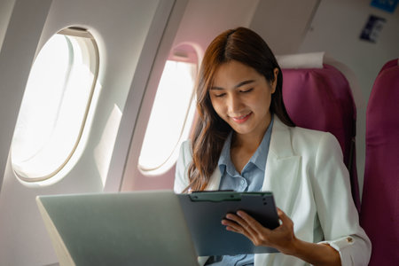 a beautiful businesswoman was traveling to negotiate a business with a business partner abroad by plane, while traveling she checked documents and worked to kill time, businessman, business tripの写真素材