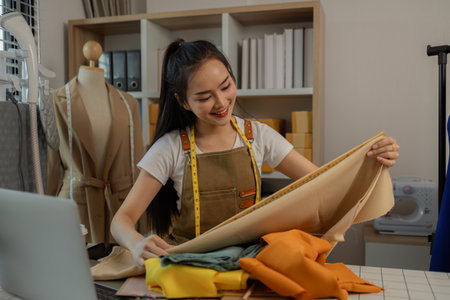 a beautiful tailor is working on her favorite craft in a studio filled with a variety of sewing supplies, fabrics and threads, designer, dressmaker, fashion, entrepreneurの写真素材